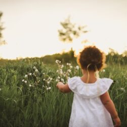 girl standing beside white flower field