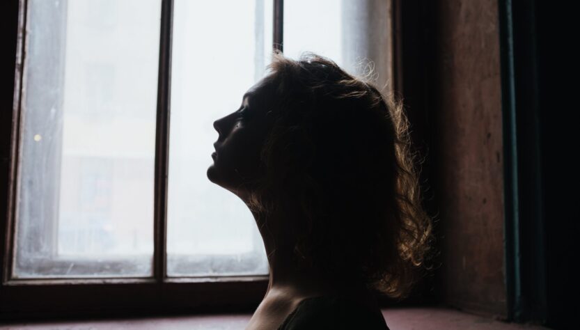 woman in black shirt looking out the window