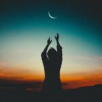 silhouette of woman reaching the moon